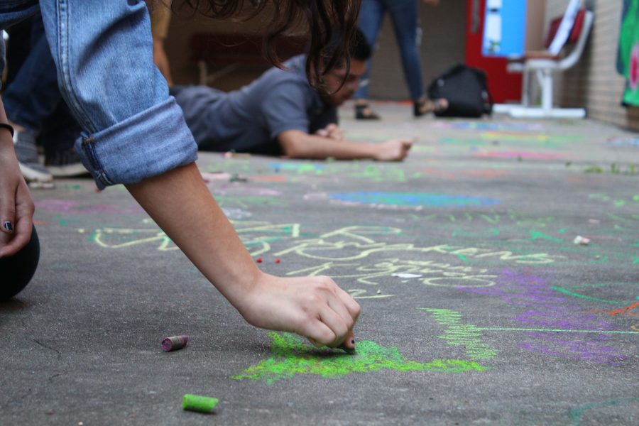 A student draws with chalk on 2016's Earth Day.